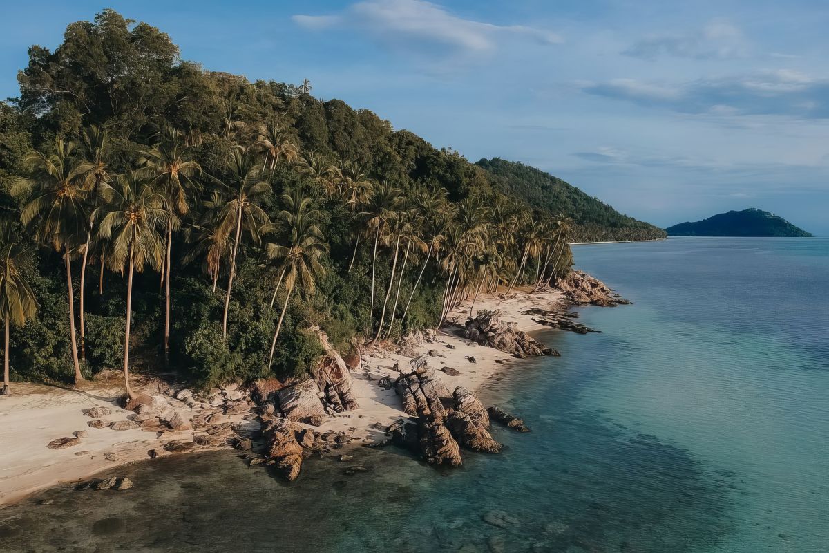 Hidden beach paradise in Taling Ngam, Koh Samui. Towering palms fringe the shore, creating a secluded tropical haven with crystal-clear waters.