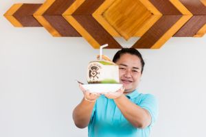 A Maya Resort Samui egyik munkatársa friss kókuszitalt tart, amely a Fisherman-s Village Bophut trópusi báját és vendégszeretetét testesíti meg.