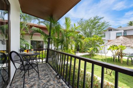 Covered balcony of a Garden Villa with table and chairs overlooking the resort garden.