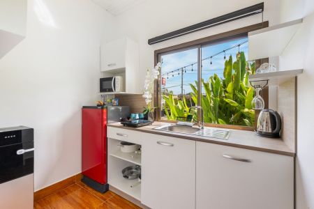 Kitchenette of a Garden Villa with microwave, red fridge, kettle and crockery.
