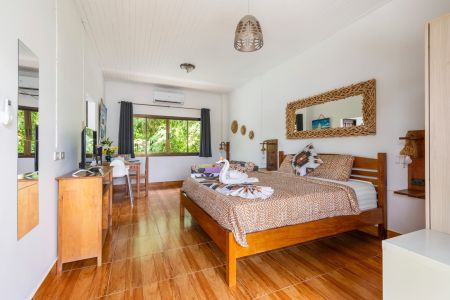 Garden Villa interior with double bed, desk, air conditioning and a window onto the greenery.