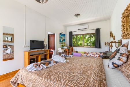 Garden Villa bedroom with television, wooden furniture and towel swans on the bed.